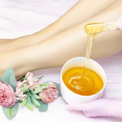 young woman having hair removal procedure on leg with sugaring paste in salon young woman having hair removal procedure on leg with sugaring paste in salon
